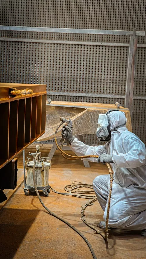 Illustrative stock photograph of a worker using spray-painting equipment in an industrial workshop